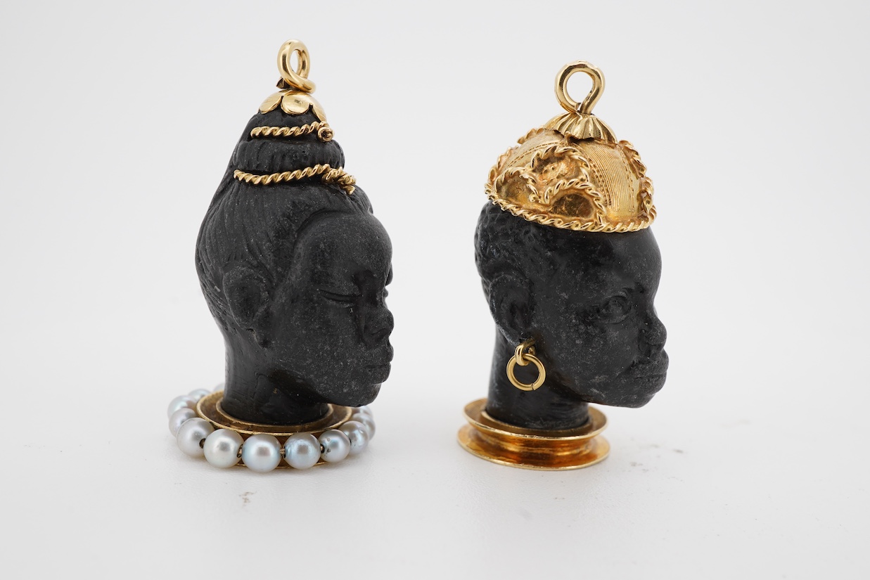 Two yellow metal mounted carved Blackamoor head charms, one with seed pearl set base, both overall approximately 30mm.